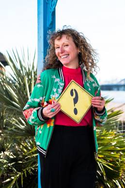 Career coaching to get the job you want. Jo Murfin Career Coach Brighton holding a yellow question mark sign.